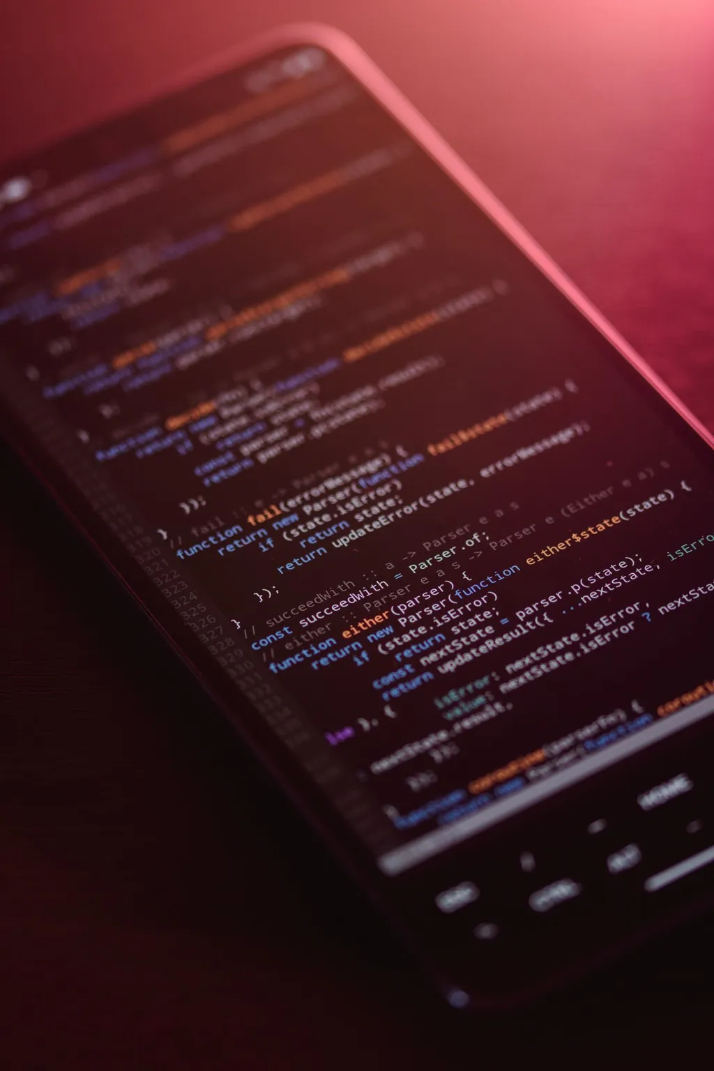 Close-up of JavaScript code on a smartphone screen lit in red and pink ambient light