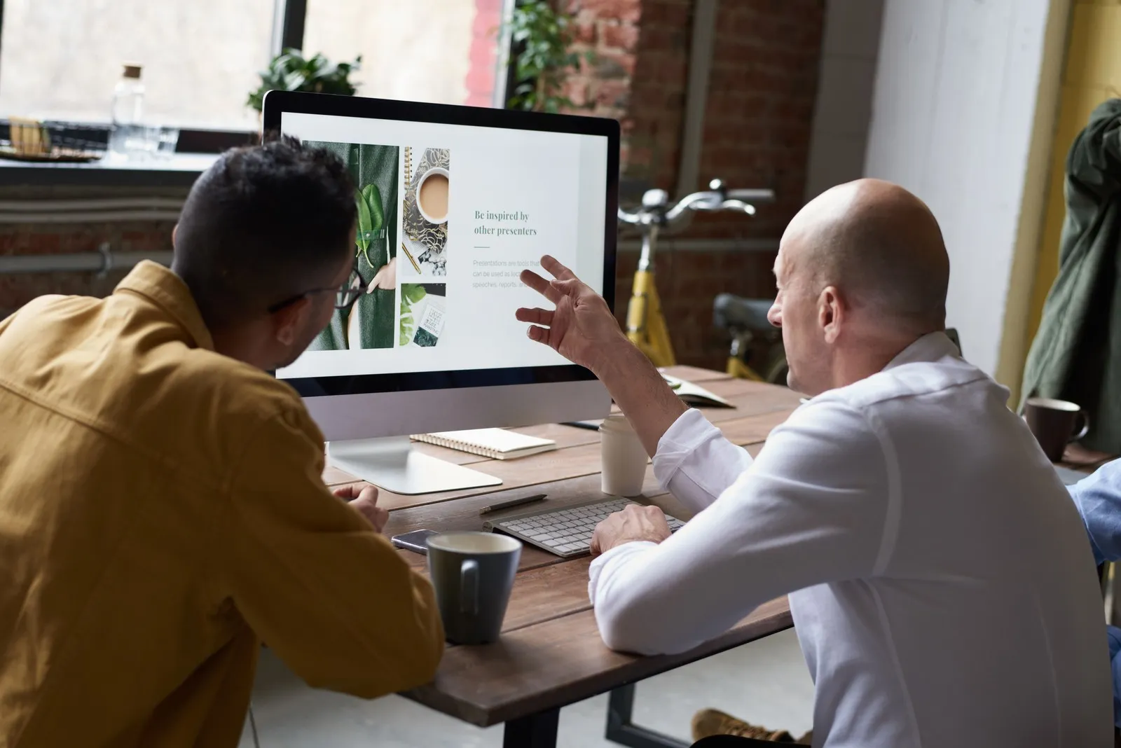 Two colleagues reviewing a design mockup together on an iMac screen