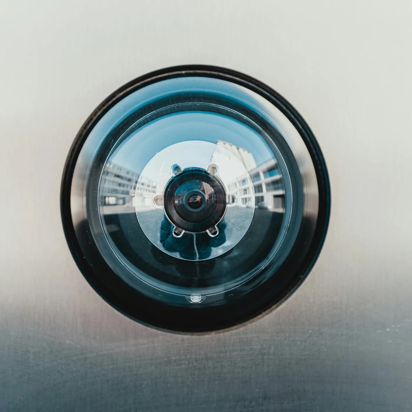 Close-up of a security camera lens mounted on a wall
